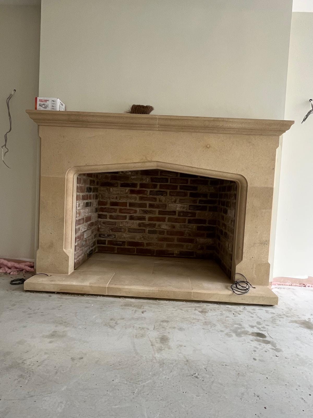A wide four-centred stone fireplace arch with a brick-lined firebox behind it and a single-slab stone hearth