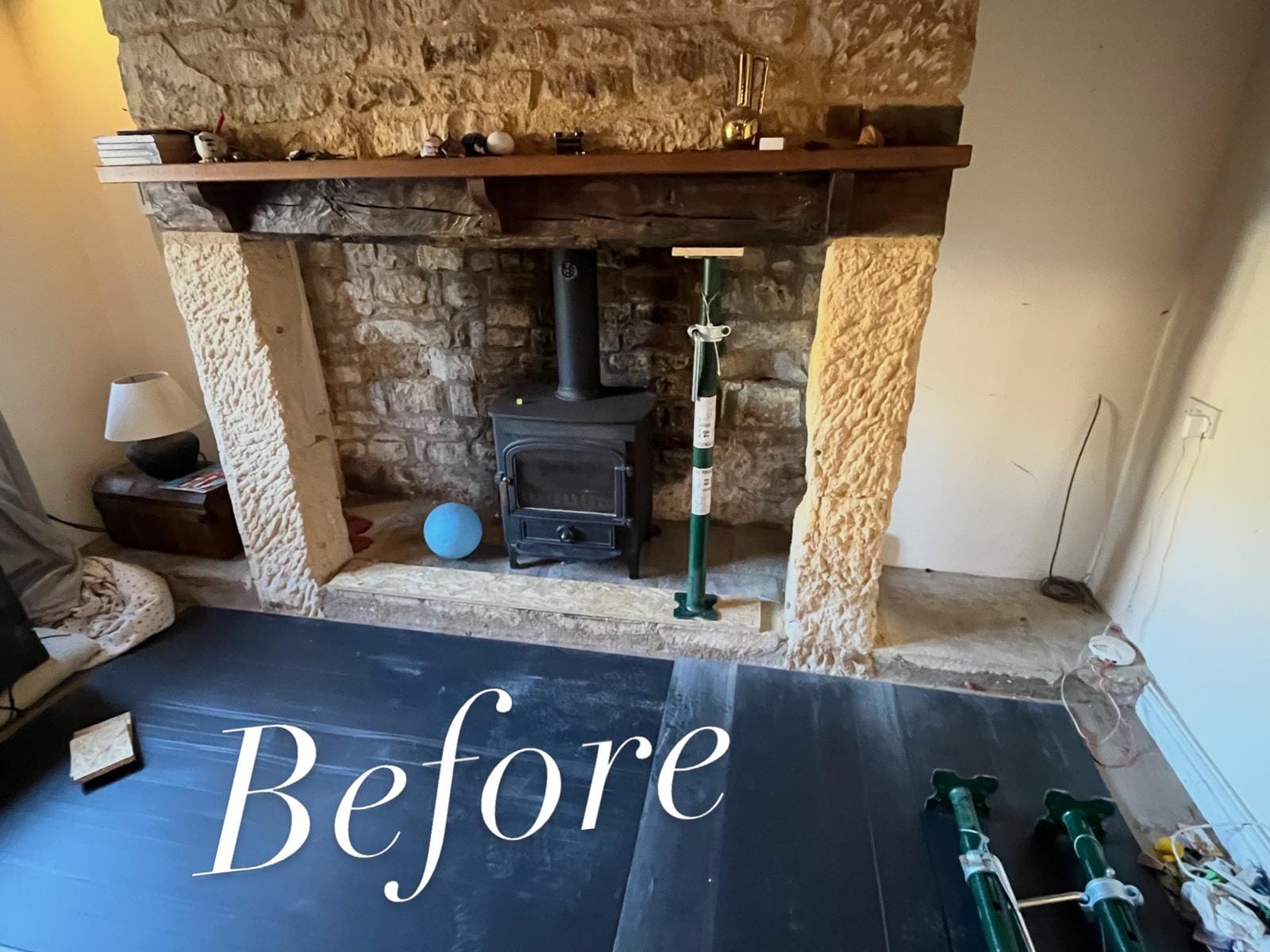 Cottage inglenook before restoration, with rough pitted stone jambs either side of the opening and an acrow prop supporting the beam