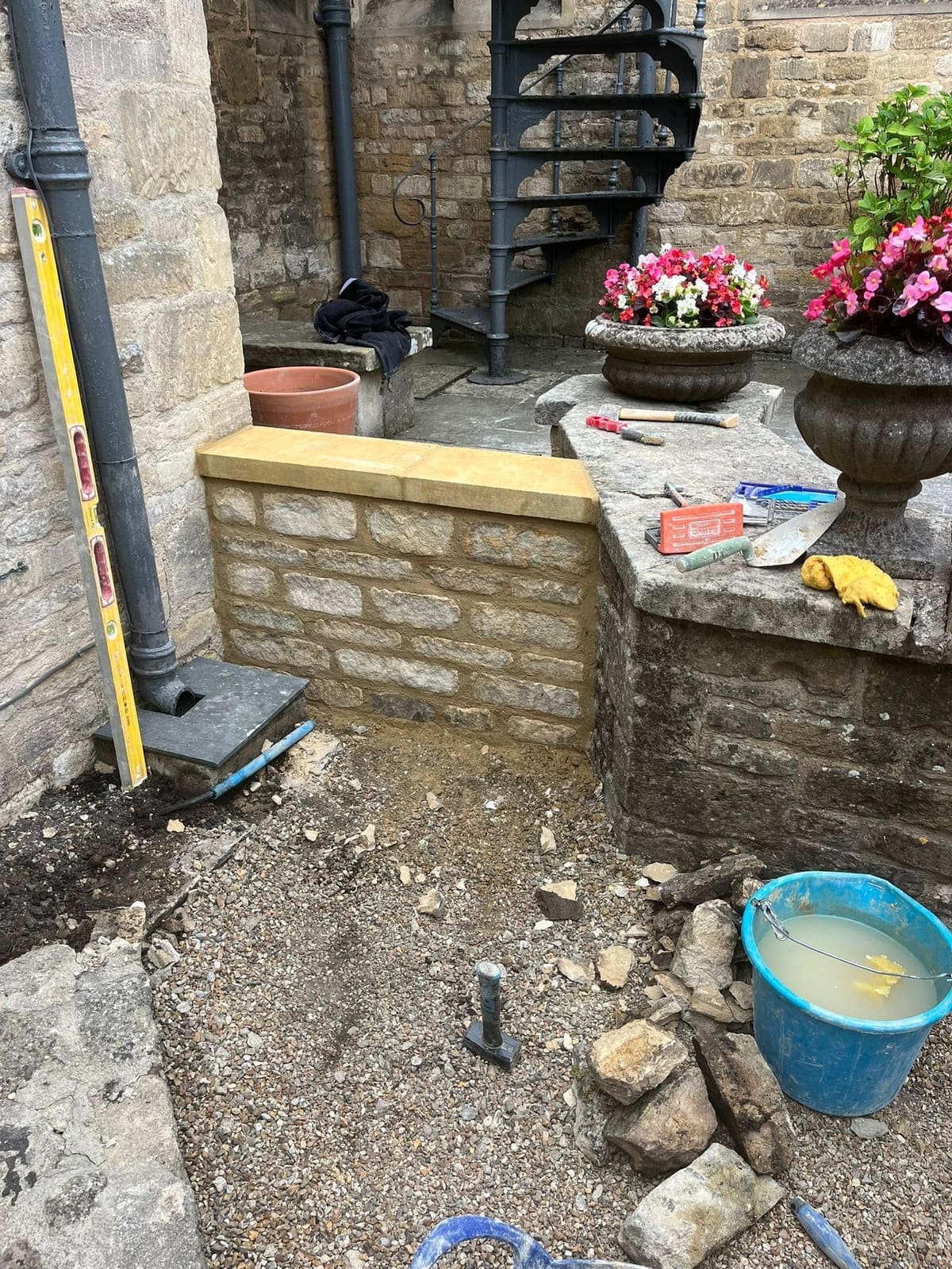 The new coursed stone wall at the Lamb Inn with its fresh dressed coping, tools still out on the old wall beside it