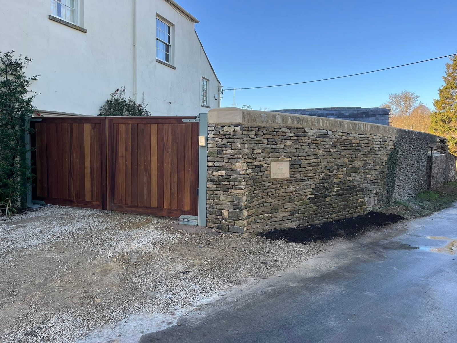 The new dry stone wall returning to timber gates, with the coping running through and older walling continuing beyond