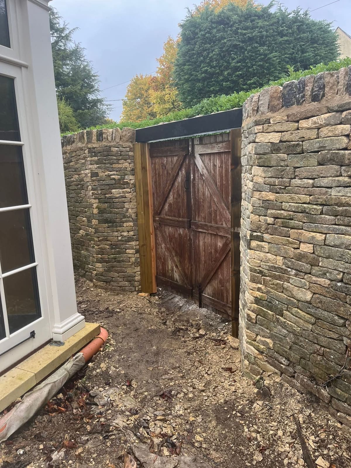 The finished gateway from inside, both dry stone cheeks framing the reused timber gates